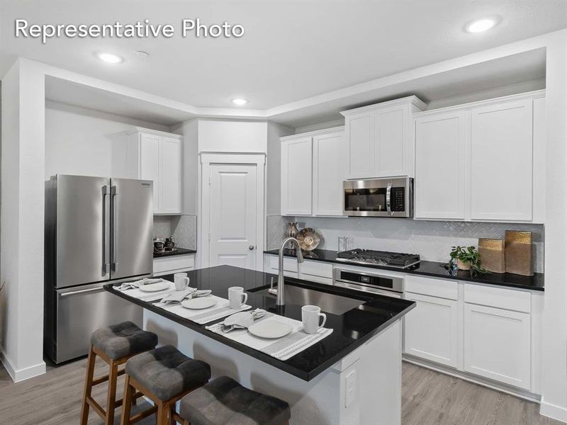 Kitchen featuring stainless steel appliances, sink, white cabinets, and light hardwood / wood-style flooring