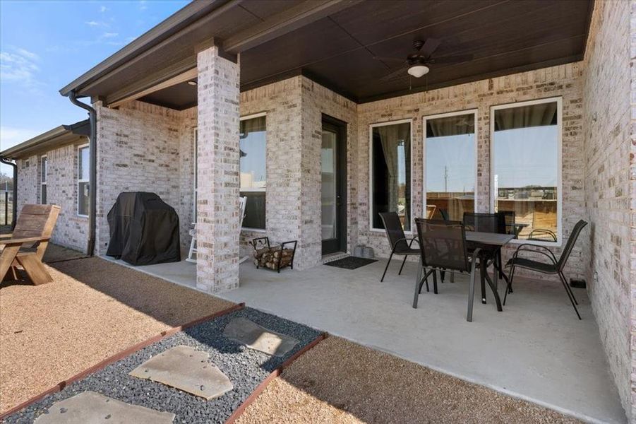 View of patio with ceiling fan, outdoor dining area, and a grill