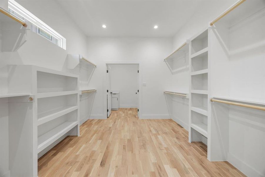 The expansive primary walk-in closet offers abundant hanging space, custom shelving, and a thoughtfully designed layout with convenient access to the laundry room for effortless everyday living. The expansive primary walk-in closet offers abundant hanging space, custom shelving, and a thoughtfully designed layout with convenient access to the laundry room for effortless everyday living.