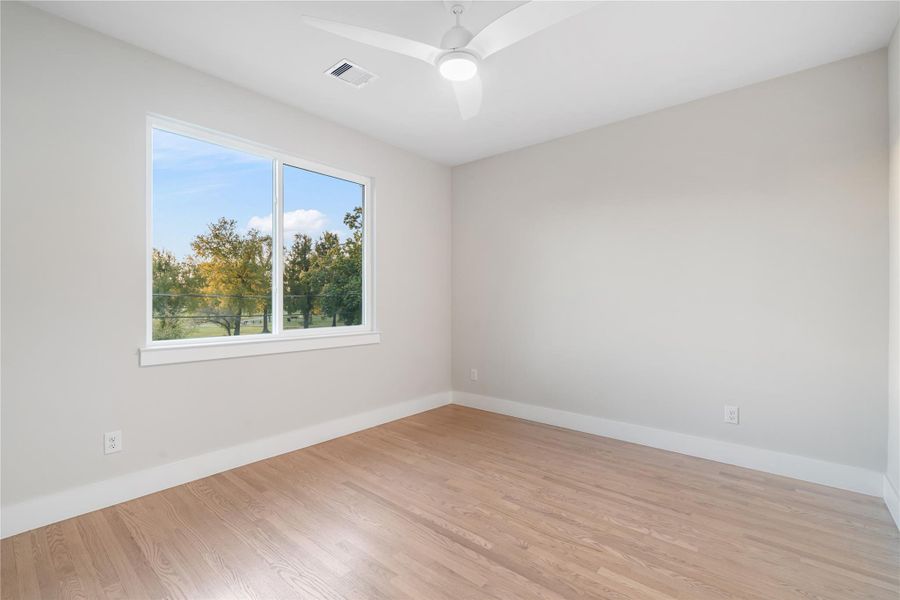 One of the secondary bedrooms, complete with a spacious walk-in closet, ceiling fan, and large custom windows that fill the room with natural light. One of the secondary bedrooms, complete with a spacious walk-in closet, ceiling fan, and large custom windows that fill the room with natural light.