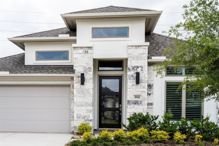 Modern home with a clean facade, featuring a stone accent wall and contemporary front door. It has a sleek garage, well-maintained landscaping, and large windows for natural light. Modern home with a clean facade, featuring a stone accent wall and contemporary front door. It has a sleek garage, well-maintained landscaping, and large windows for natural light.