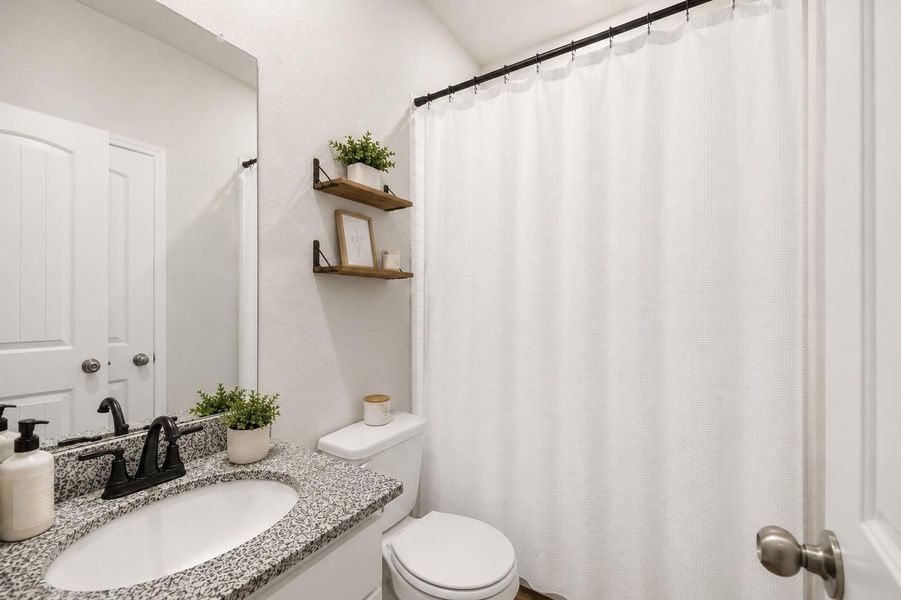 Charming 1st floor full bathroom featuring a sleek granite countertop, modern fixtures, and stylish floating shelves