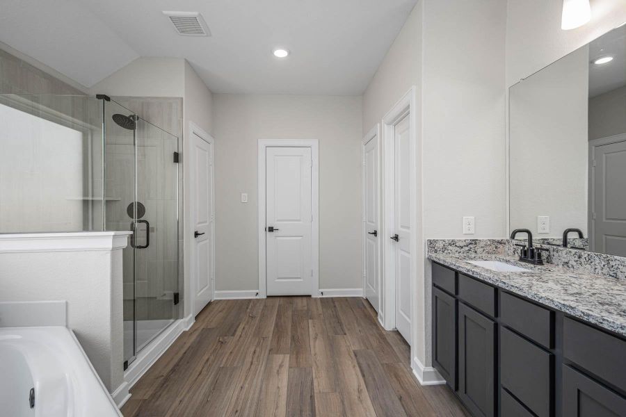 The primary bathroom features corner soaking tube, tiled walk in shower, and double closets