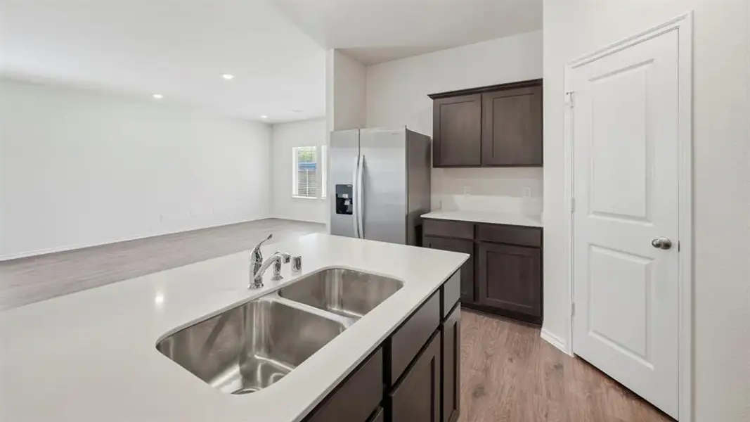 Kitchen featuring light wood finished floors, stainless steel fridge with ice dispenser, recessed lighting, dark brown cabinetry, and open floor plan