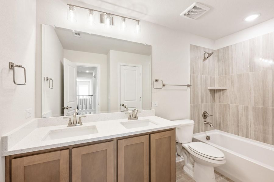 Bathroom with double sink vanity, white quartz countertop, and tiled tub-shower combo Bathroom with double sink vanity, white quartz countertop, and tiled tub-shower combo