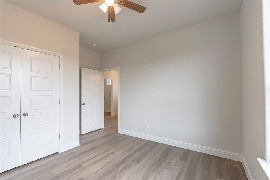 Unfurnished bedroom with ceiling fan, a closet, and light wood-type flooring