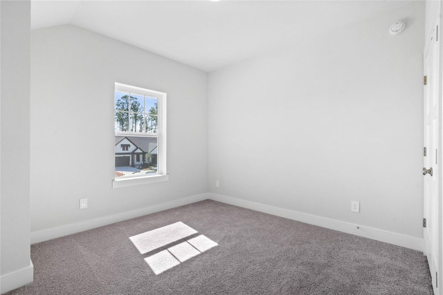 Discover a peaceful sanctuary in this inviting secondary bedroom, perfectly designed for comfort. It features sloped ceiings and a generously sized window providing ample natural light.