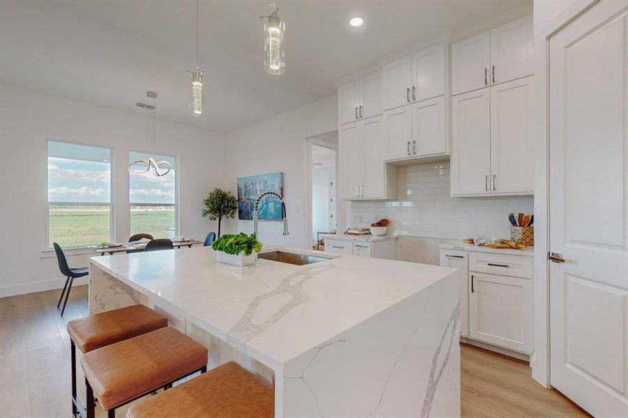 Kitchen with light hardwood / wood-style floors, a center island with sink, sink, and hanging light fixtures