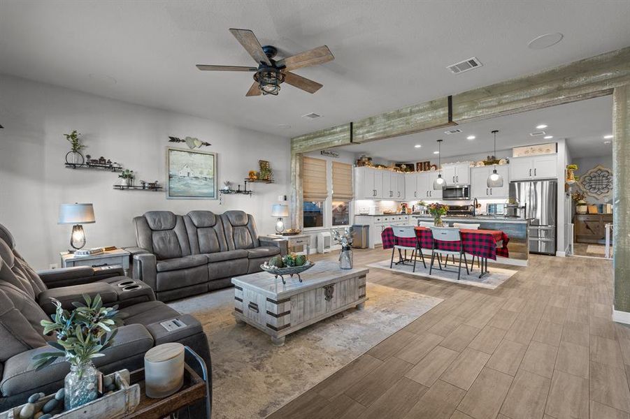 Living room with ceiling fan, light wood-type flooring, and sink