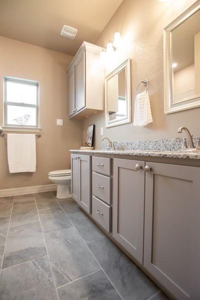 Full bathroom with double vanity, a sink, baseboards, toilet, and marble finish floor