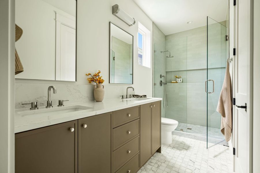 Dual vanities with sleek hardware provide ample space in this contemporary primary bathroom.