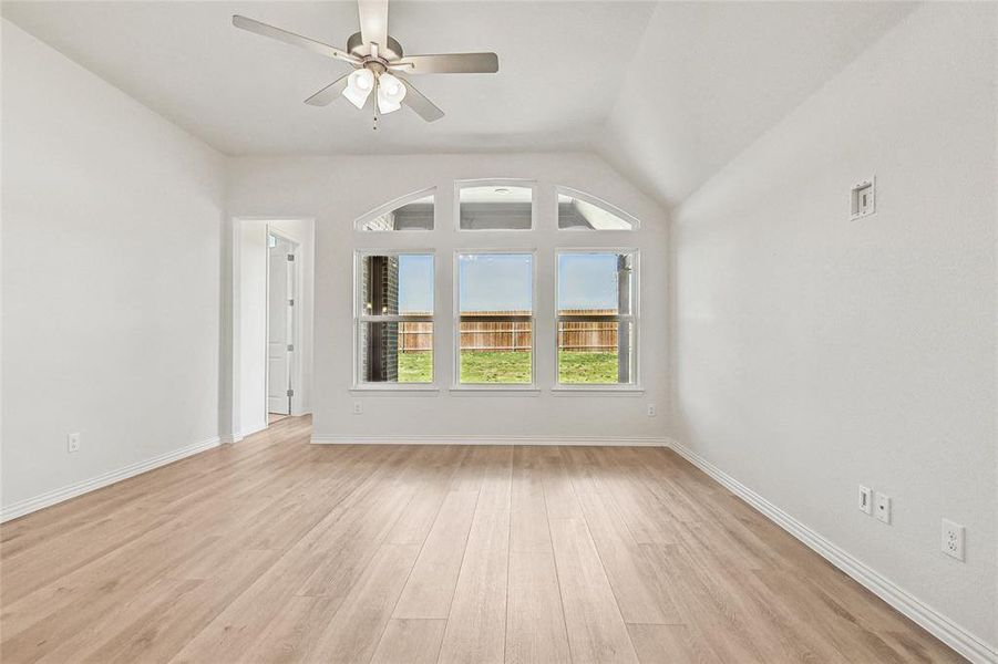 Empty room featuring light hardwood / wood-style floors, vaulted ceiling, and ceiling fan