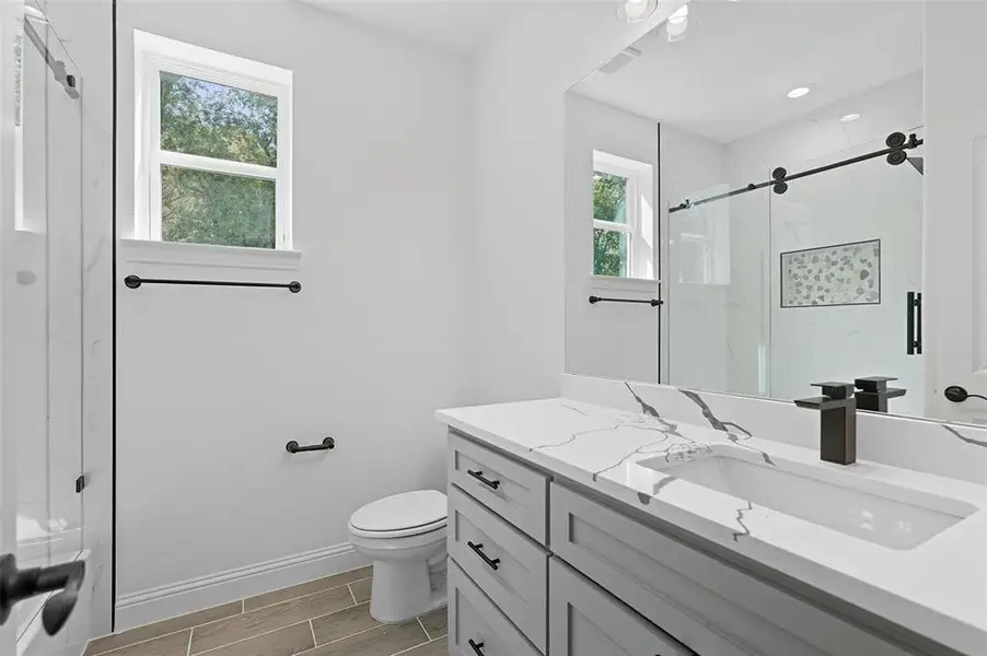 Full bath with a marble finish shower, vanity, and wood finish floors Full bath with a marble finish shower, vanity, and wood finish floors