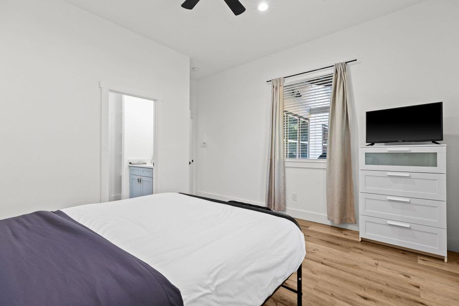 Bedroom featuring light wood-style floors, ceiling fan, and connected bathroom