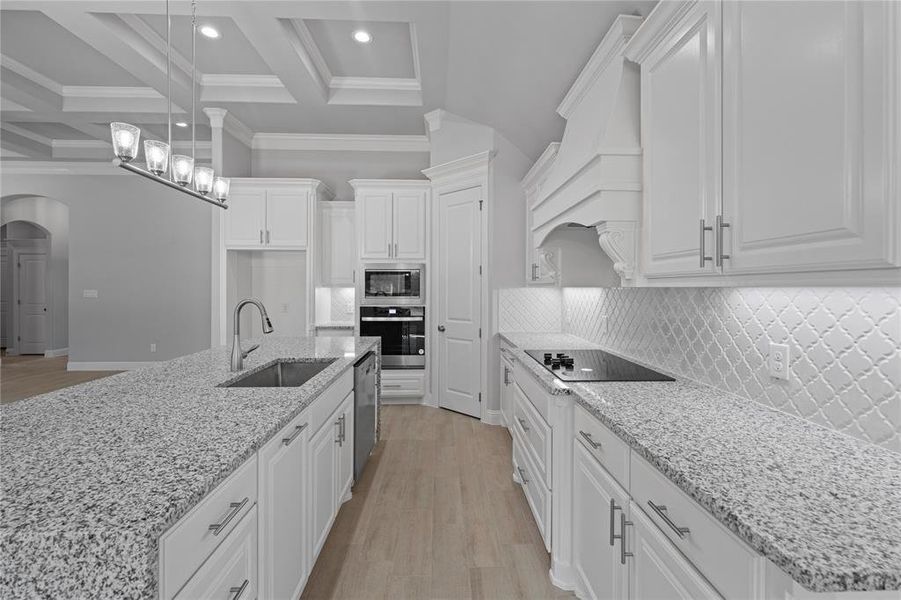 Kitchen with appliances with stainless steel finishes, sink, white cabinetry, beamed ceiling, and premium range hood