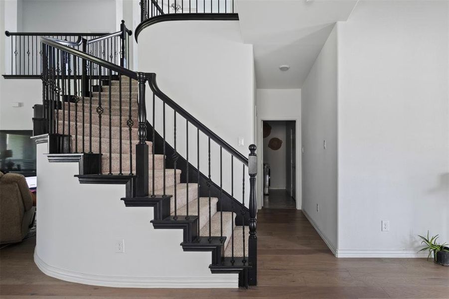 Stairway with wood finished floors and a high ceiling
