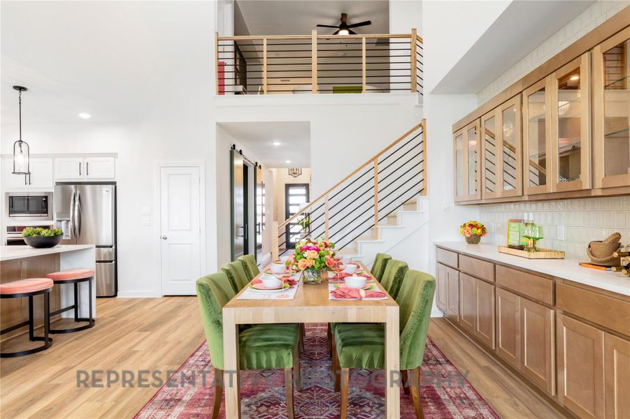 Dining room featuring light wood-style floors, ceiling fan, recessed lighting, stairs, and a towering ceiling