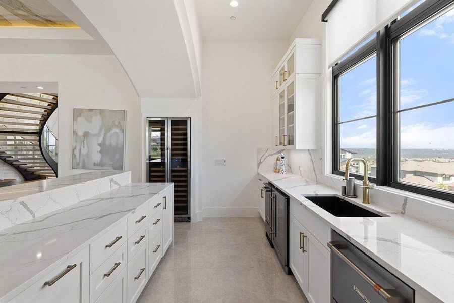 A refined wet bar with sleek cabinetry, a dedicated wine refrigerator, and a scenic window view.