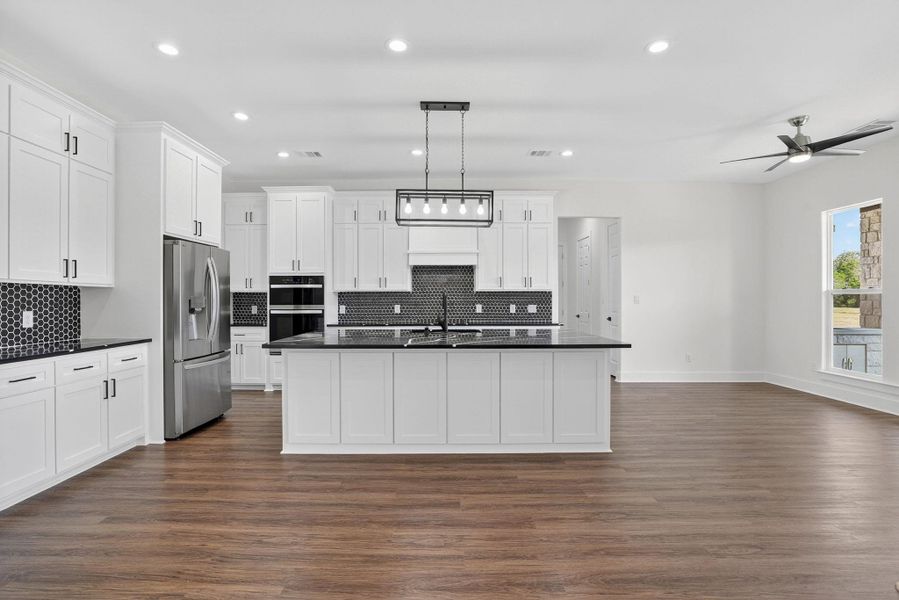 Kitchen with stainless steel fridge, hanging light fixtures, recessed lighting, white cabinets, and dark wood finished floors Kitchen with stainless steel fridge, hanging light fixtures, recessed lighting, white cabinets, and dark wood finished floors