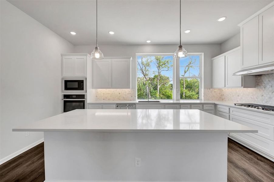 Kitchen featuring a spacious island with a white countertop, recessed lighting, pendant lights, wood-finish flooring, and white cabinetry