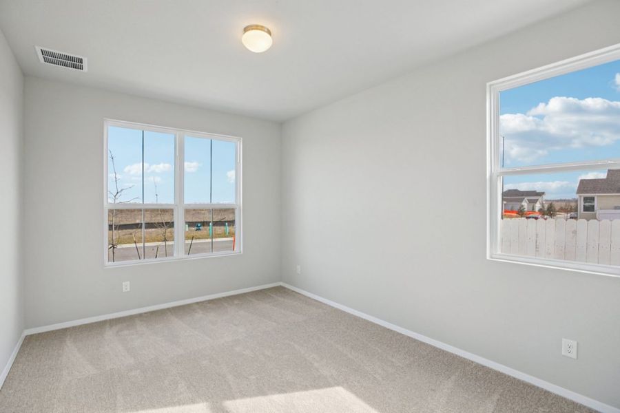 Image of a primary bedroom with light grey walls, tan carpeting, windows and white trim Image of a primary bedroom with light grey walls, tan carpeting, windows and white trim