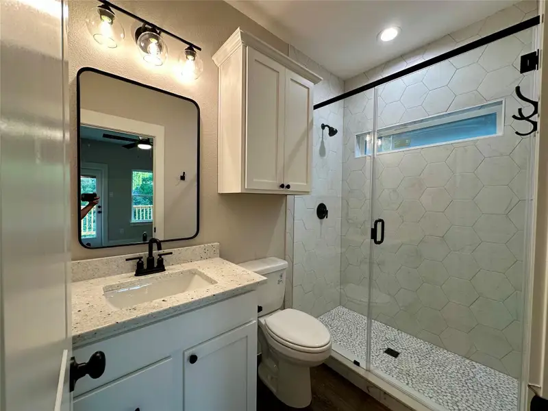 Bathroom featuring vanity, a stall shower, wood finished floors, and ceiling fan