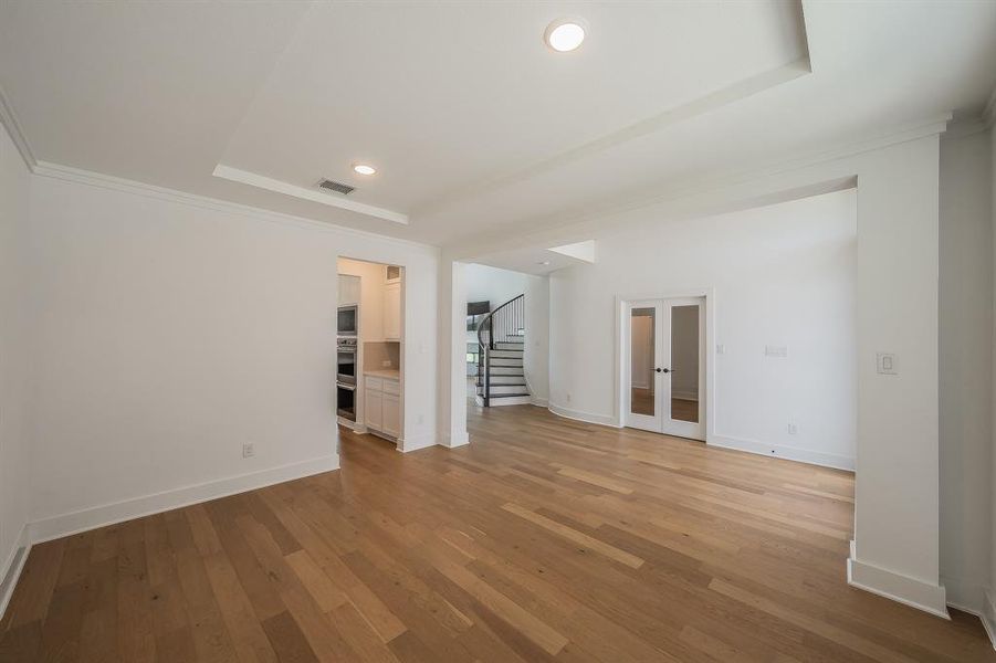 Expansive living area featuring hardwood floors, recessed lighting, and a tray ceiling