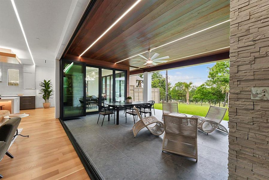 Covered outdoor living area featuring a wood-finish ceiling with integrated lighting and a ceiling fan