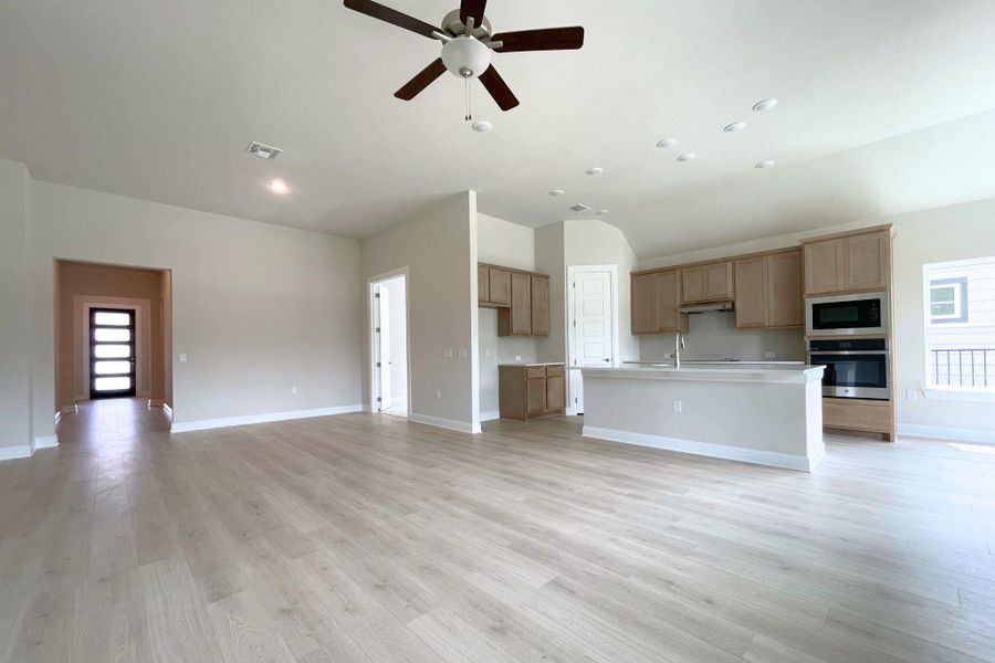 An open concept living area features light wood flooring and a modern kitchen with a large island.