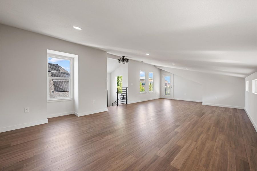 Unfurnished living room with vaulted ceiling, plenty of natural light, recessed lighting, and wood finished floors