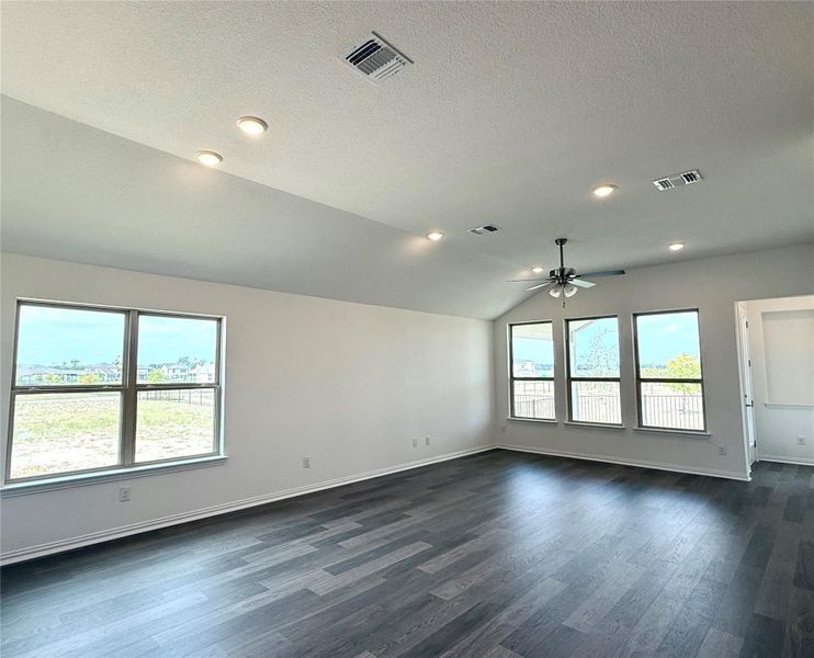 Spare room with dark wood finished floors, lofted ceiling, ceiling fan, a textured ceiling, and recessed lighting Spare room with dark wood finished floors, lofted ceiling, ceiling fan, a textured ceiling, and recessed lighting