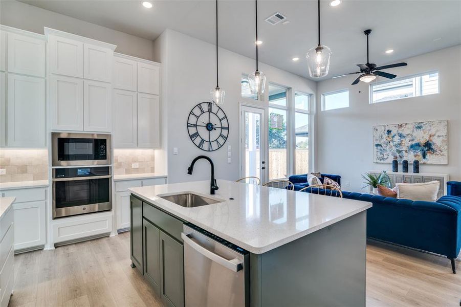 Kitchen with a center island with sink, decorative backsplash, sink, and stainless steel appliances