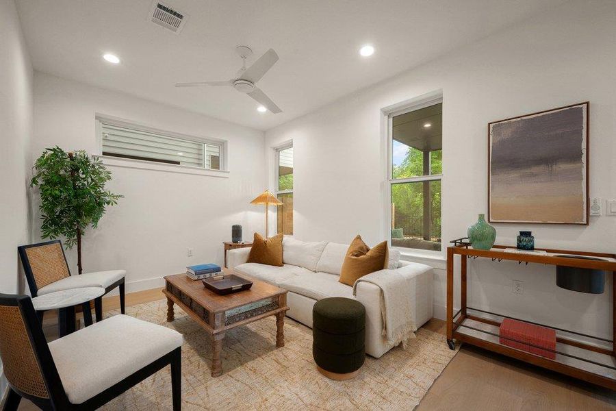 Recessed lighting illuminates this bright dual living room/den/bedroom or flex space, featuring a sleek ceiling fan and ample natural light through tall windows. Recessed lighting illuminates this bright dual living room/den/bedroom or flex space, featuring a sleek ceiling fan and ample natural light through tall windows.