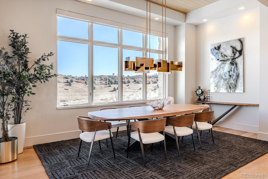 Open yet defined, the dining area occupies a glass-wrapped corner overlooking the golf course and mountains. Tongue-and-groove ceiling detailing adds texture and intimacy, while the generous proportions easily accommodate celebrations of scale.