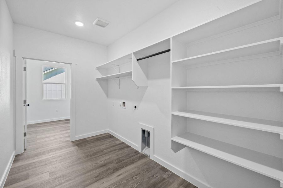 Ample shelving and hanging space complement the functional laundry setup, ready for appliances. Ample shelving and hanging space complement the functional laundry setup, ready for appliances.