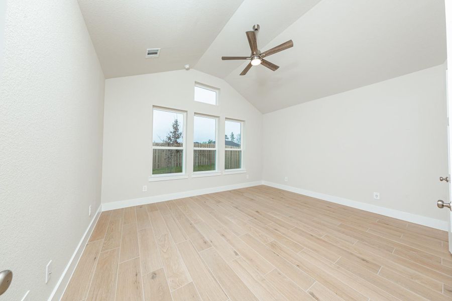 Relax and unwind after a long day in this impressive primary suite! This generously sized room offers tile plank flooring, neutral-toned paint, high ceilings with a ceiling fan, and large windows for added comfort and tranquility.