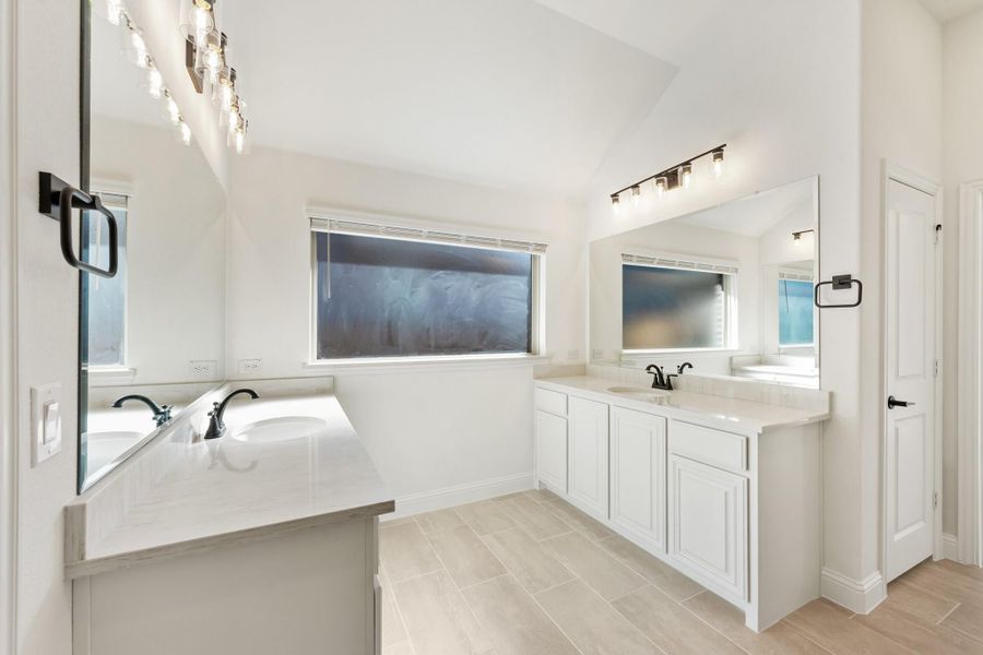 Spacious master bathroom with dual vanities, white cabinets, soaking tub, and vaulted ceiling Spacious master bathroom with dual vanities, white cabinets, soaking tub, and vaulted ceiling