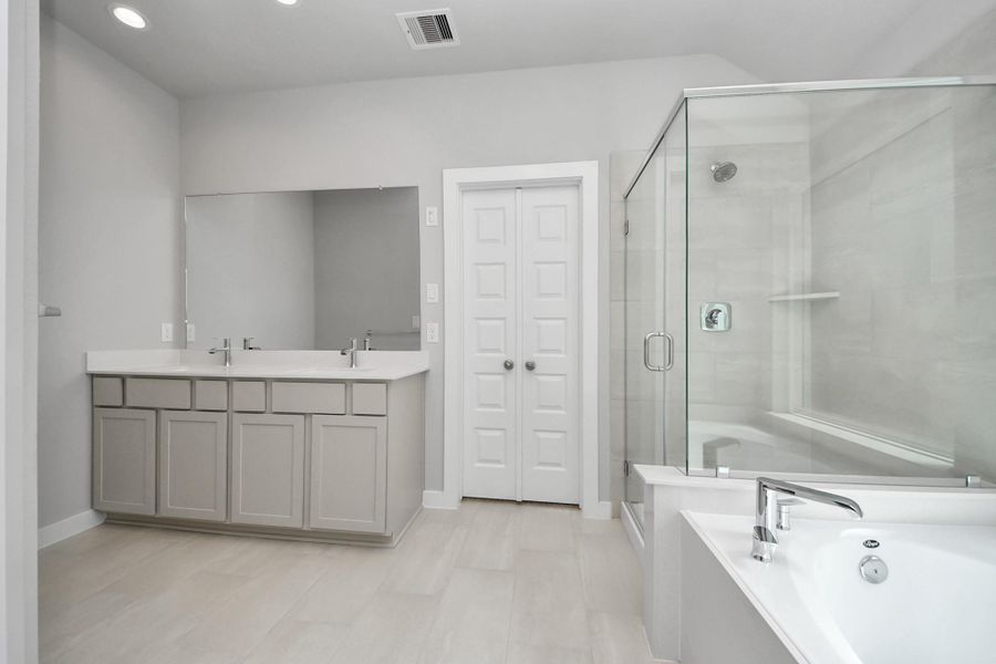 Elevate your daily routine at the elegant vanity, now equipped with double sinks, light countertops, modern hardware, and beautiful recessed lights. Sample photo of completed home with similar floor plan. Actual colors and selections may vary.