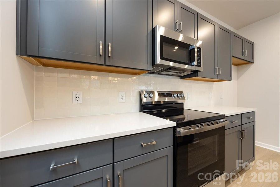 Kitchen with rich grey cabinets with white quartz countertops