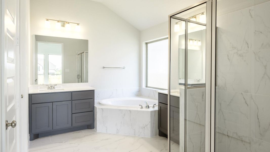 Full bath with vaulted ceiling, a marble finish shower, a garden tub, and plenty of natural light Full bath with vaulted ceiling, a marble finish shower, a garden tub, and plenty of natural light