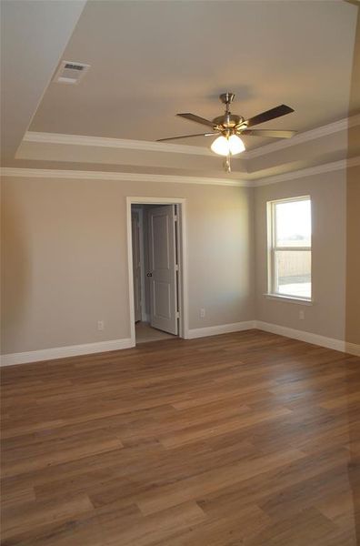 Unfurnished room featuring hardwood / wood-style flooring, crown molding, ceiling fan, and a tray ceiling