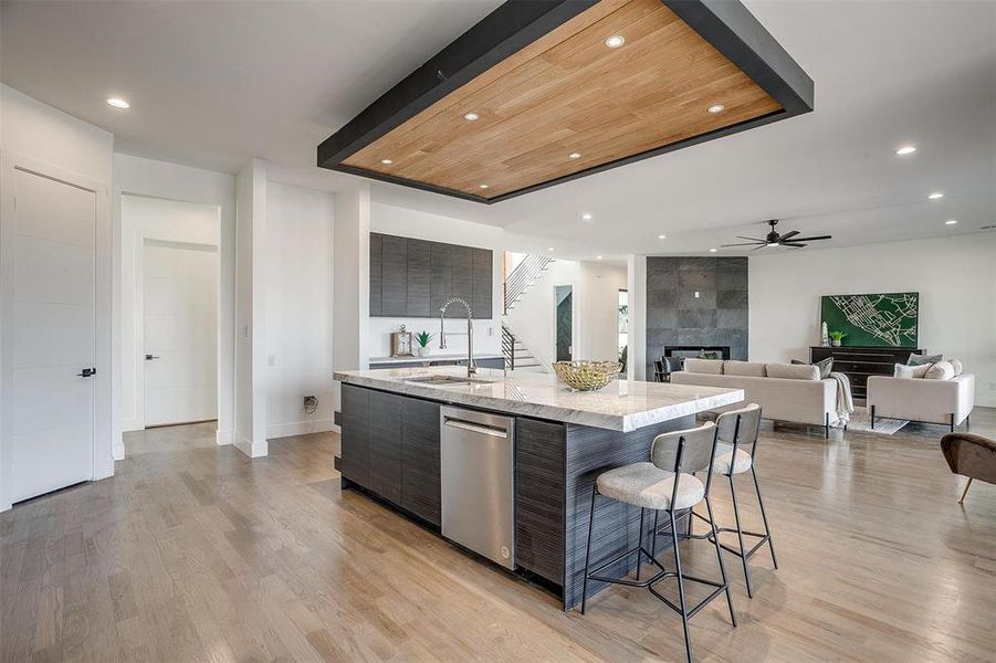 Kitchen featuring a tiled fireplace, light wood-style floors, a sink, modern cabinets, and dishwasher