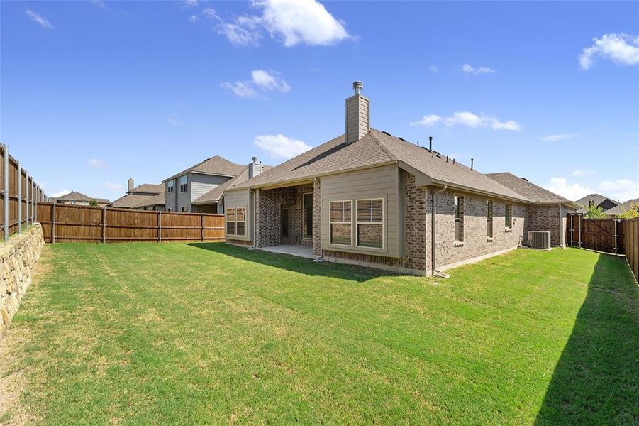 Back of house featuring a patio area, a fenced backyard, a chimney, brick siding, and a shingled roof Back of house featuring a patio area, a fenced backyard, a chimney, brick siding, and a shingled roof