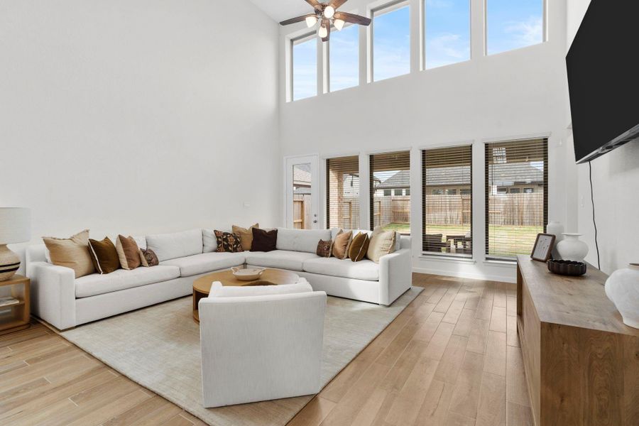 Grand living area featuring soaring double-height ceilings, a wall of massive windows for abundant natural light, and modern wood-look flooring. Grand living area featuring soaring double-height ceilings, a wall of massive windows for abundant natural light, and modern wood-look flooring.