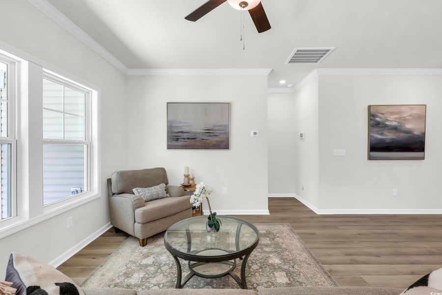 Living room with ornamental molding, wood finished floors, a ceiling fan, and recessed lighting