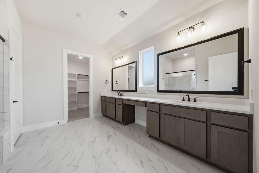 Owner’s bath offers dual vanities, abundant cabinetry, and convenient access to the generous walk-in closet.