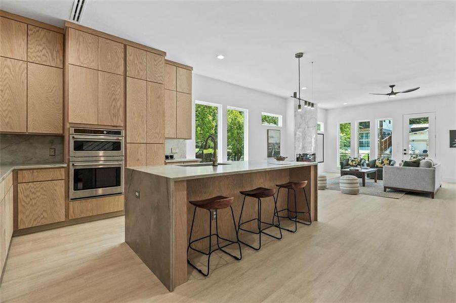 Kitchen featuring plenty of natural light, modern cabinets, a kitchen bar, light wood-style flooring, and recessed lighting Kitchen featuring plenty of natural light, modern cabinets, a kitchen bar, light wood-style flooring, and recessed lighting