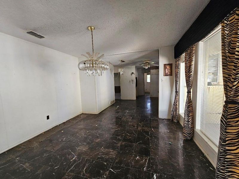 Unfurnished dining area featuring a chandelier, a textured ceiling, and a ceiling fan Unfurnished dining area featuring a chandelier, a textured ceiling, and a ceiling fan