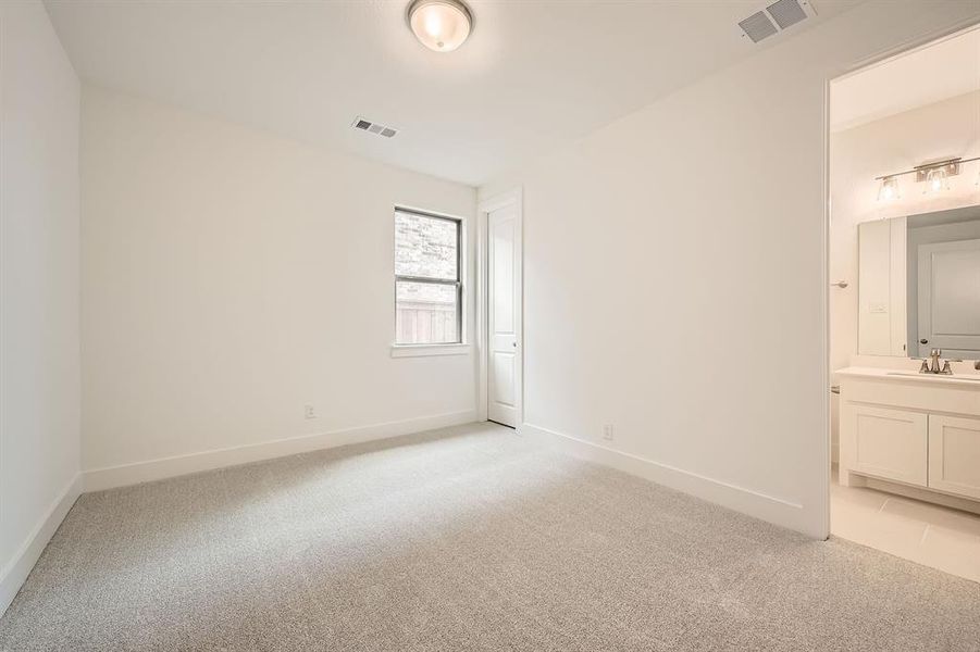 Unfurnished bedroom with light colored carpet and ensuite bath