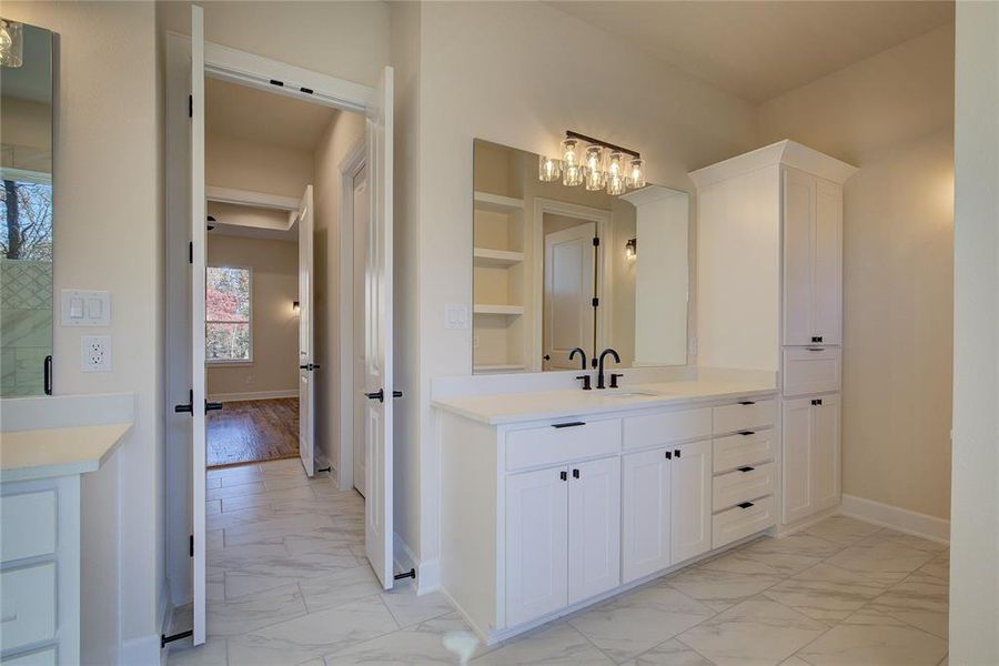 Primary bath has his'n'hers vanities with lots of extra storage.